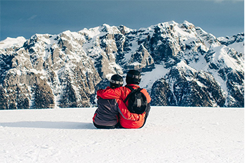 couple sitting in the snow admiring the view